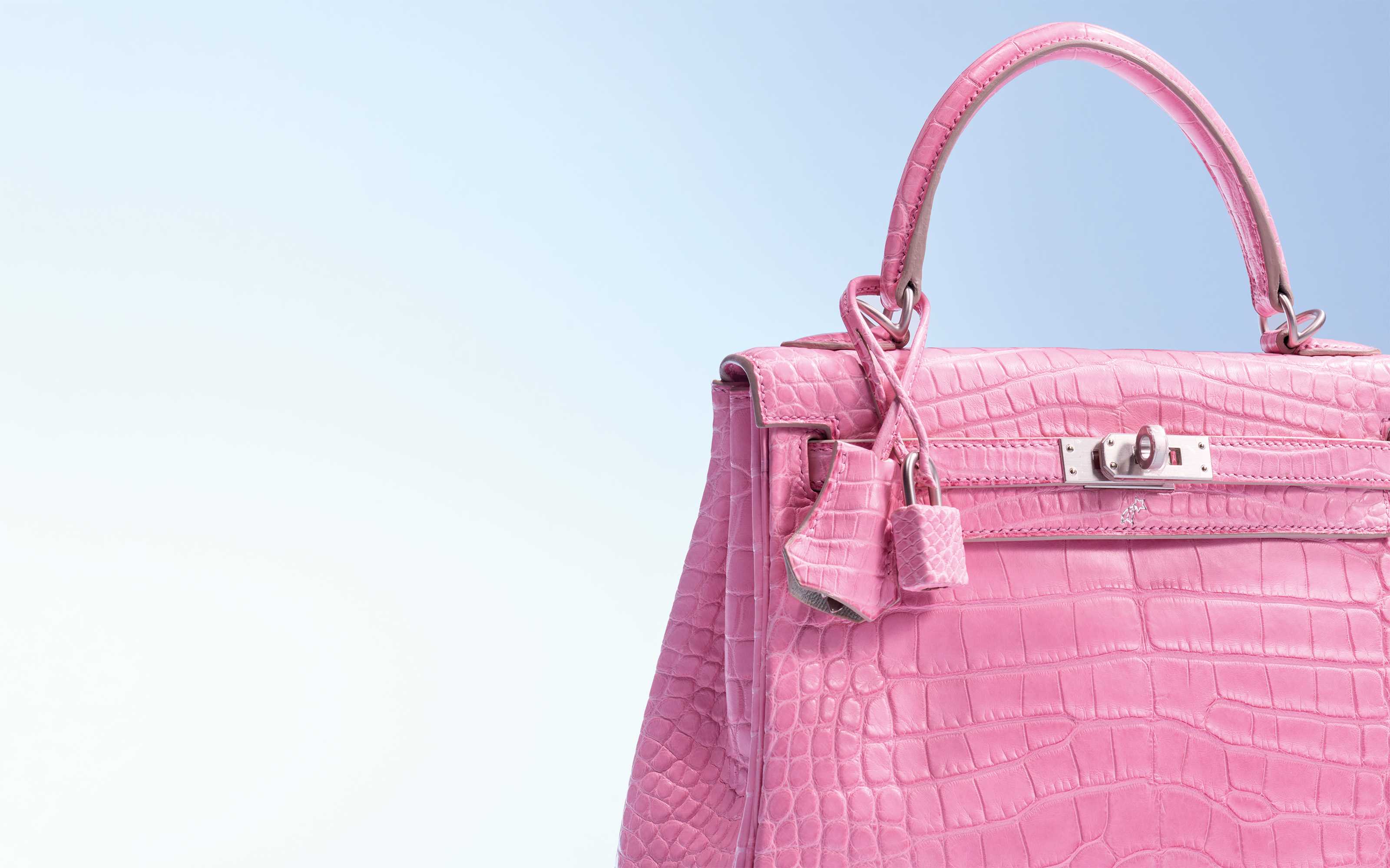 A luxury blue and black handbag with crocodile texture and geometric front design, adorned with a small padlock.